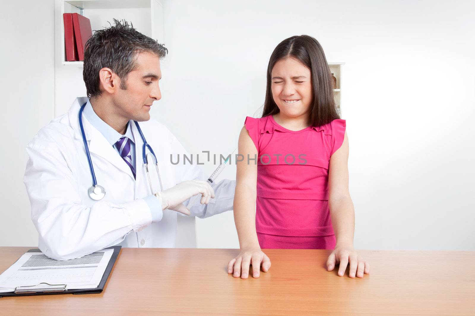 Doctor giving child patient injection in clinic.