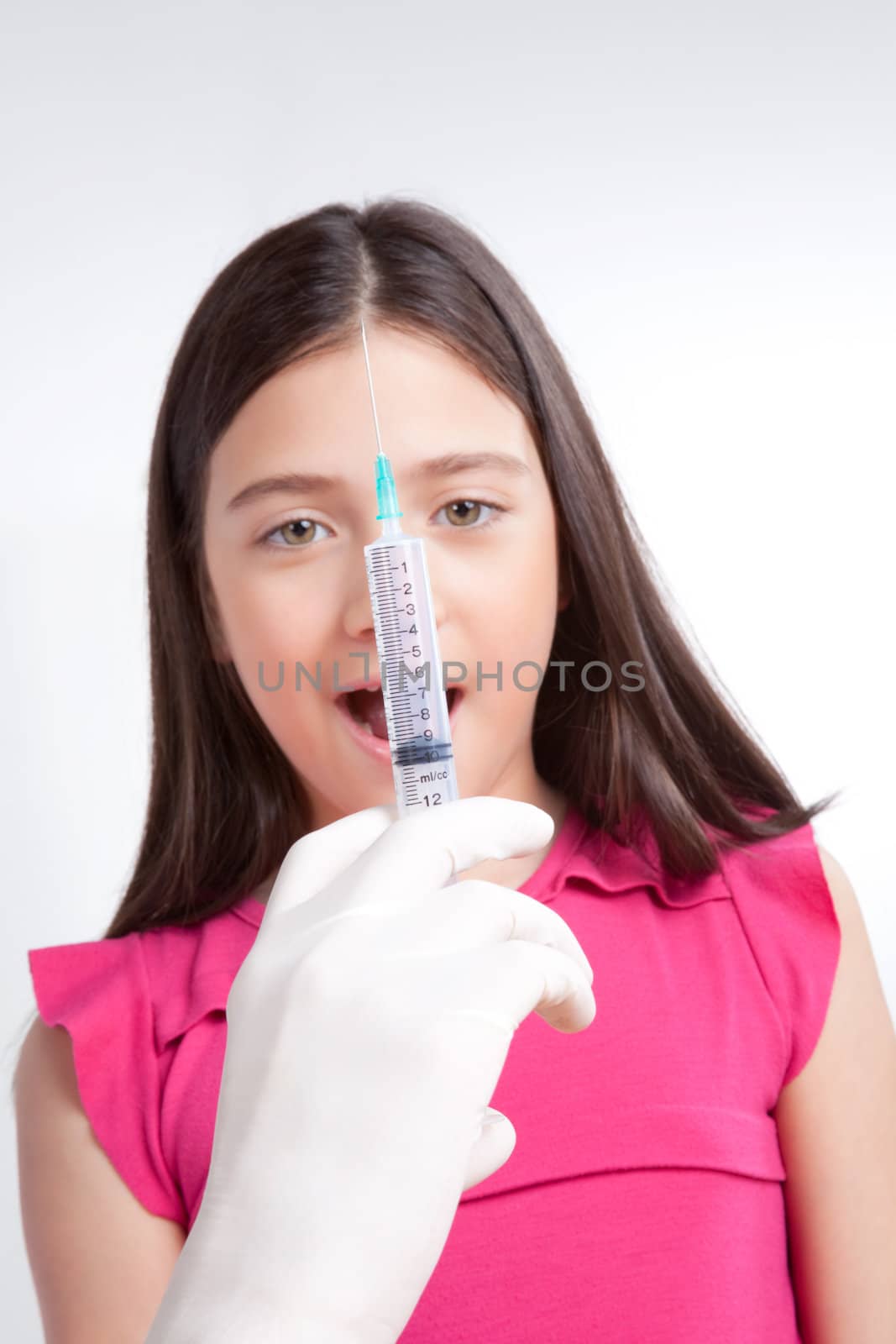 Doctor hand holding injection in front of girl.