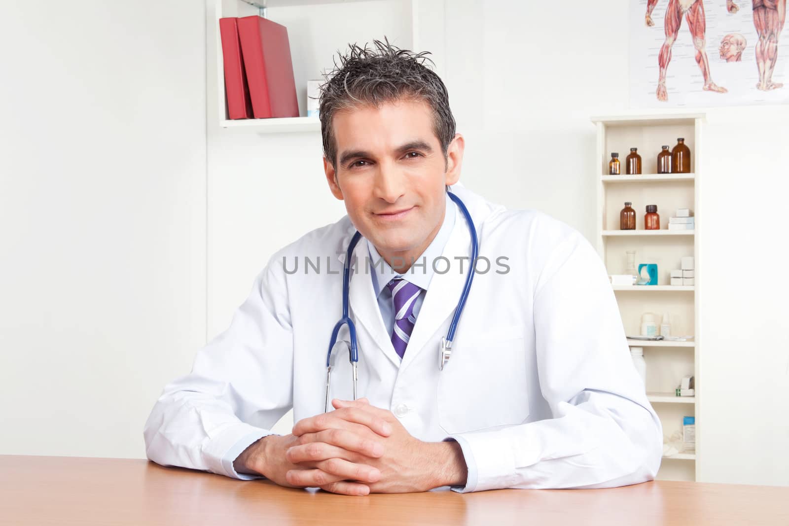 Portrait of male doctor sitting at desk .