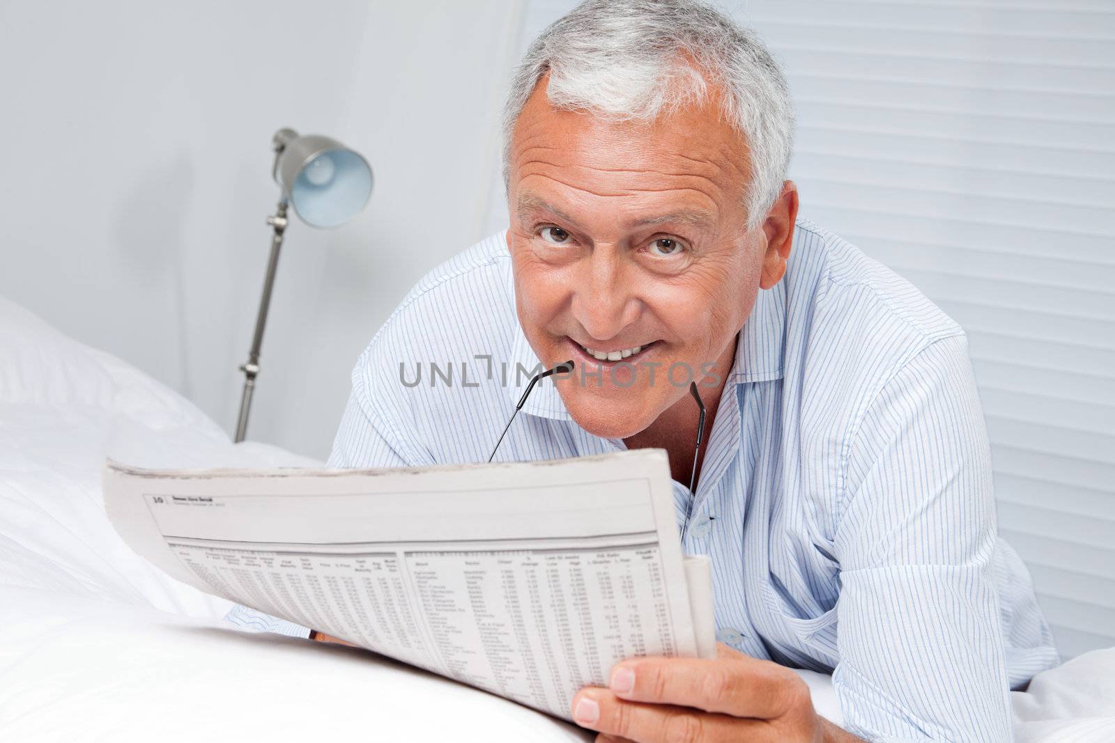 Man Reading Newspaper on Bed by leaf