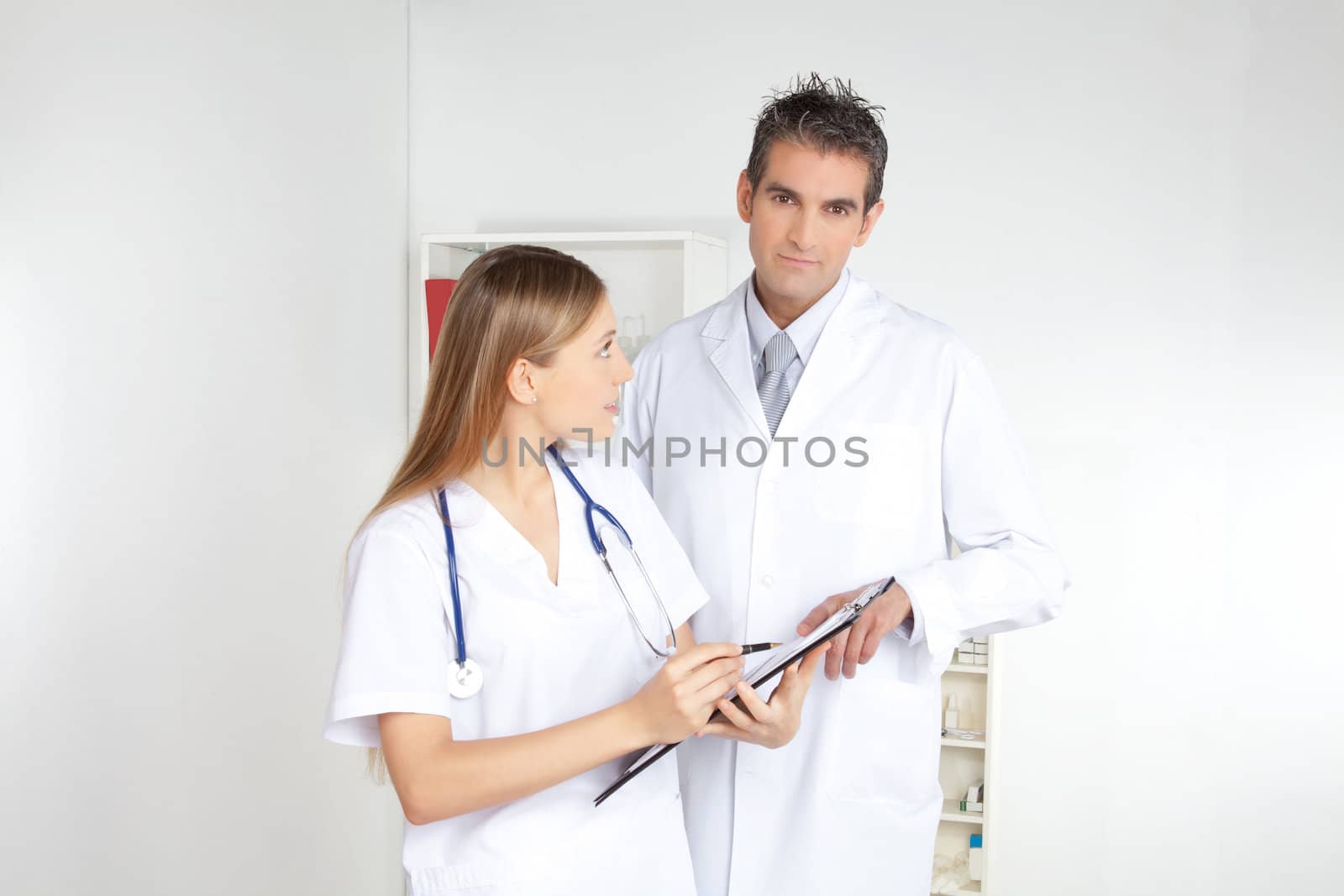 Smiling female doctor showing clipboard to the male doctor.