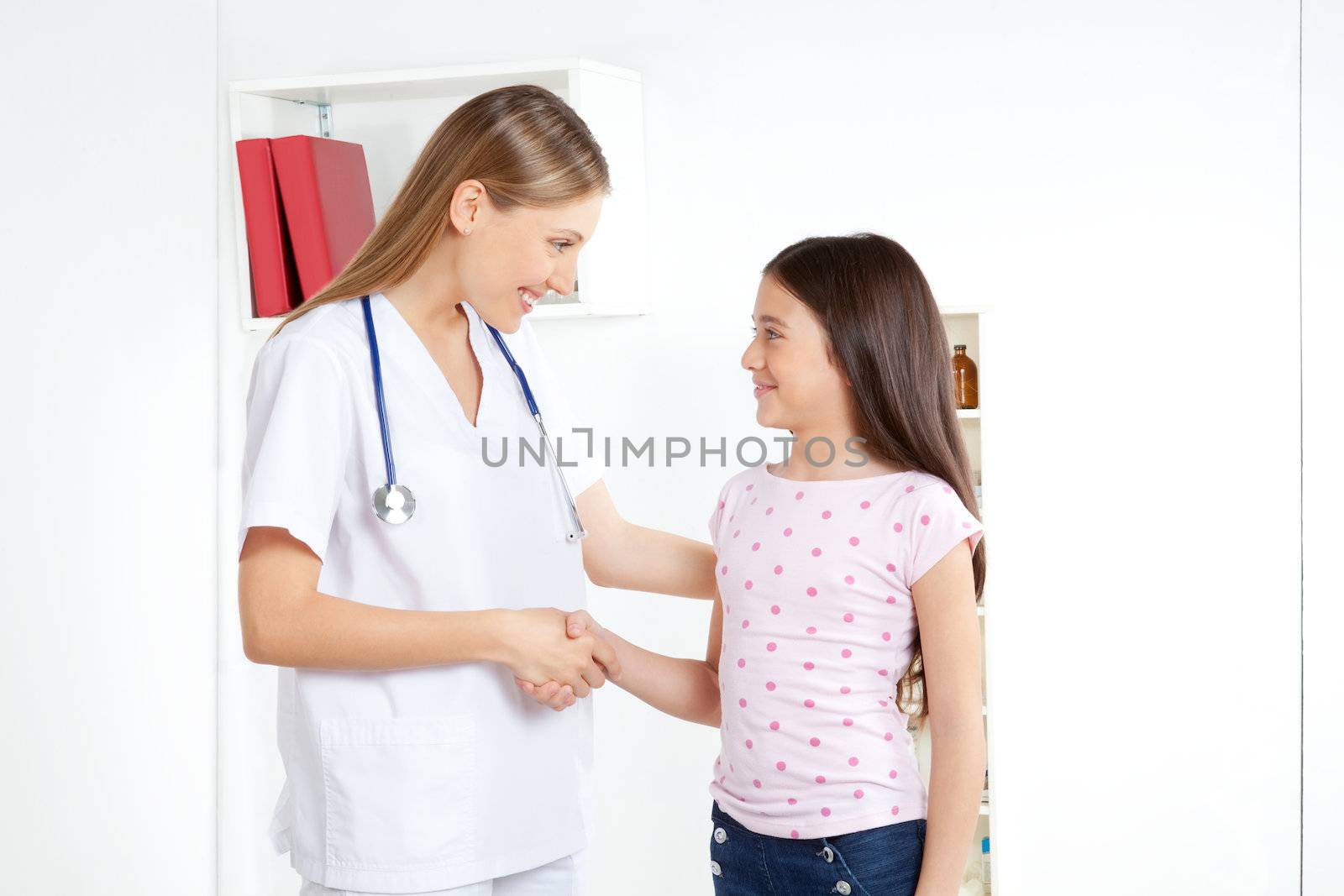 Doctor shaking hand with girl child patient.