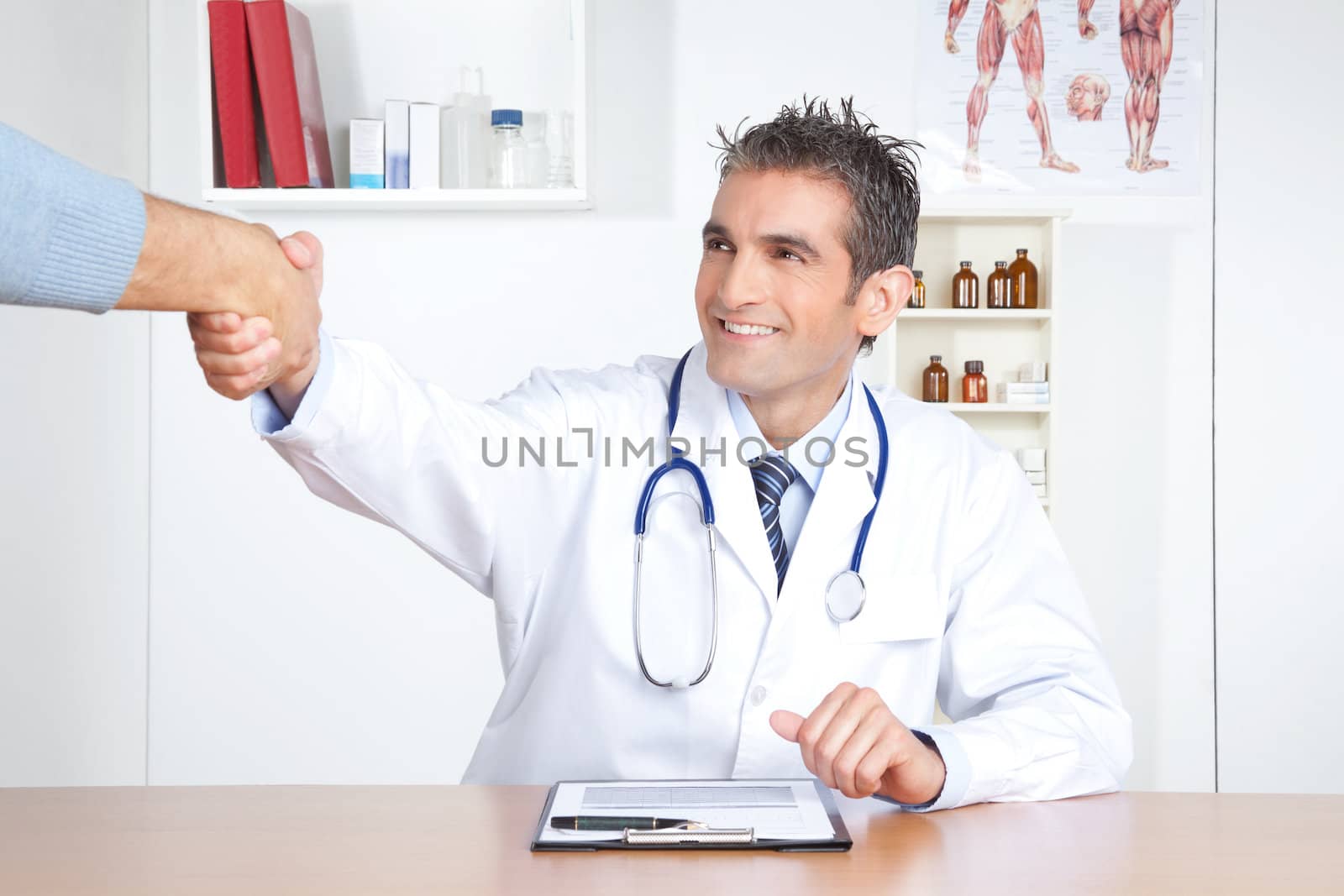 Young male doctor and patient shake hands at clinic.
