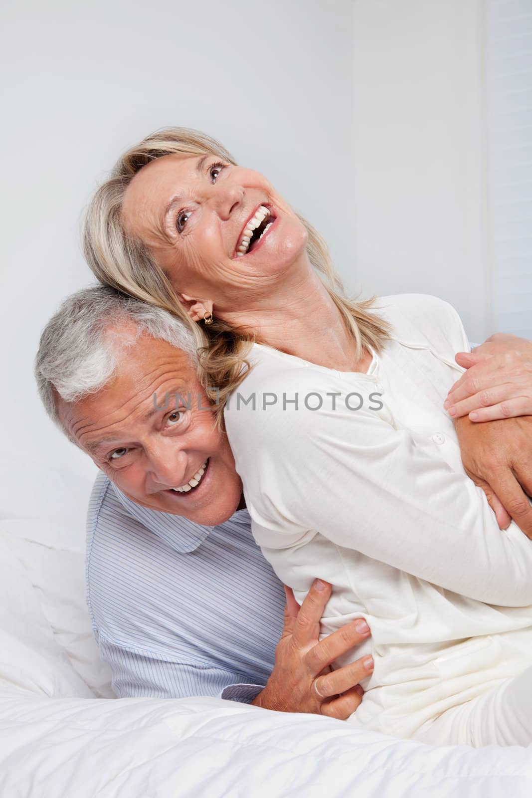 Excited senior couple laughing together on bed
