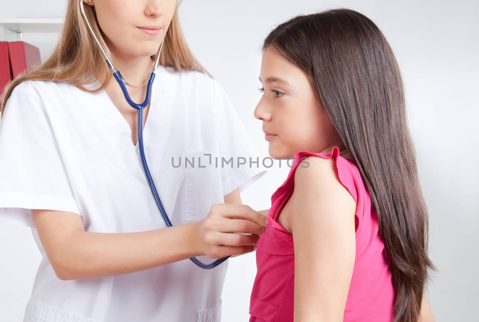 Female doctor examining child patient in clinic.