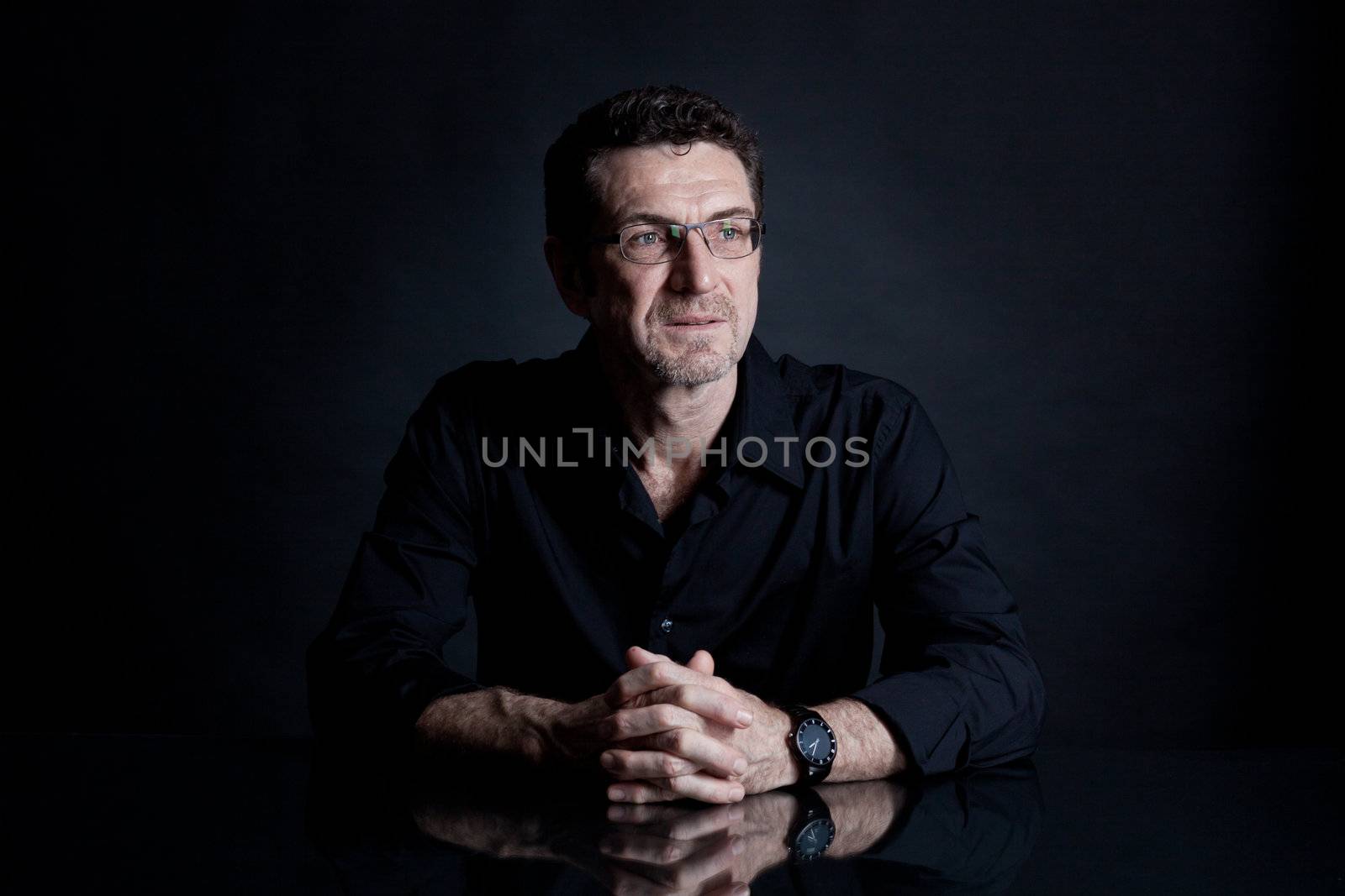 attractive adult man with glasses and black shirt on black background