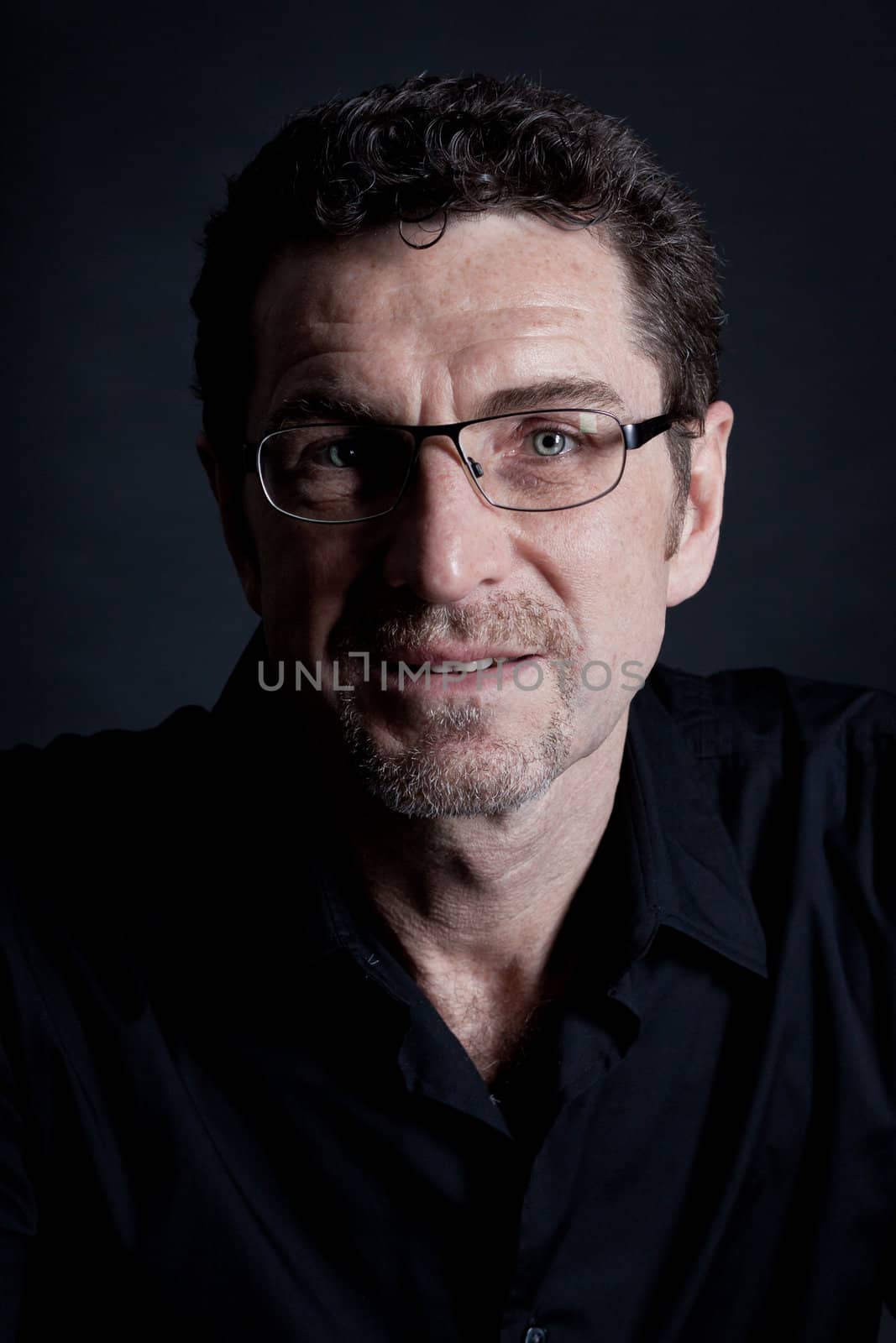 attractive adult man with glasses and black shirt on black background