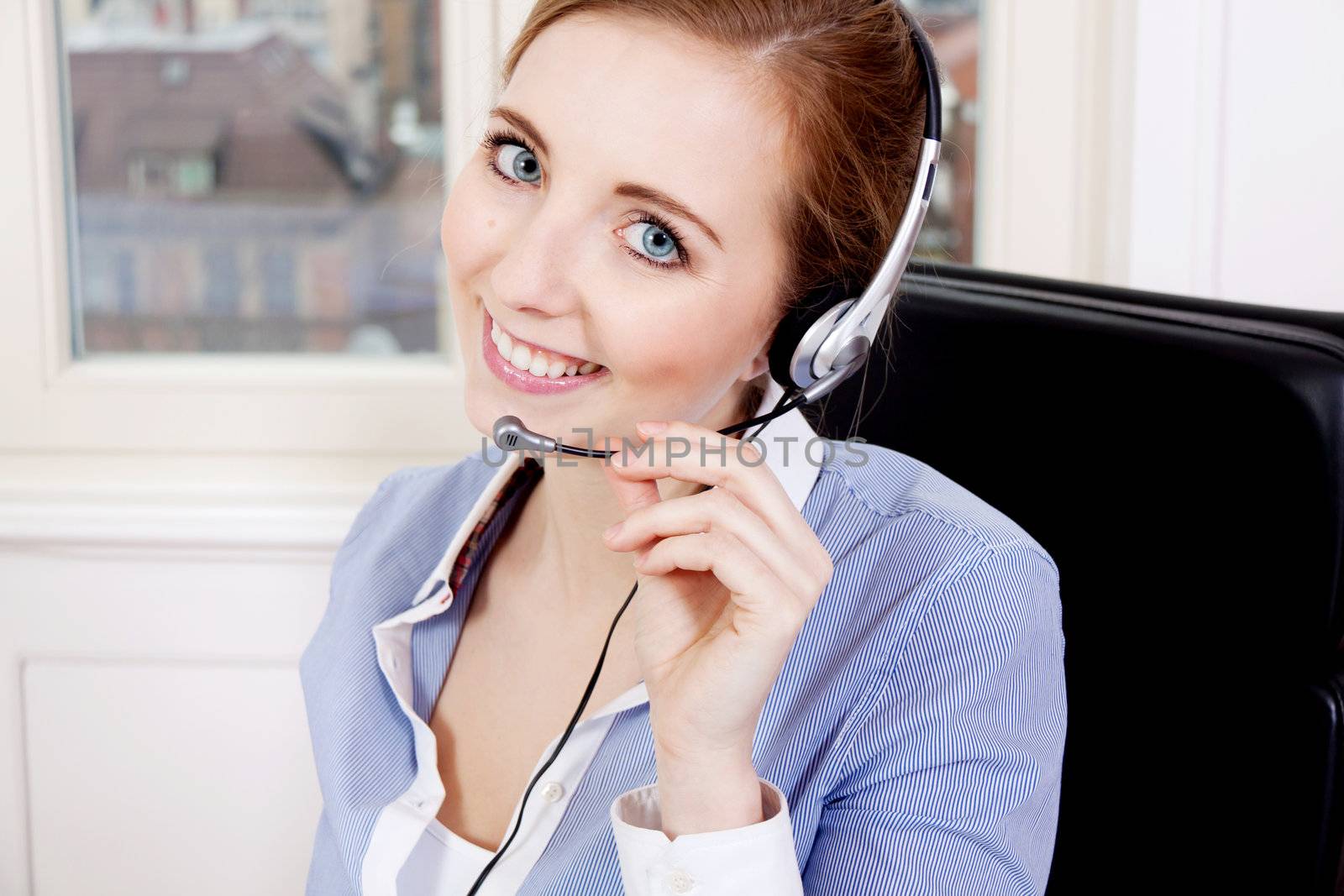 smiling young female callcenter agent with headset in office