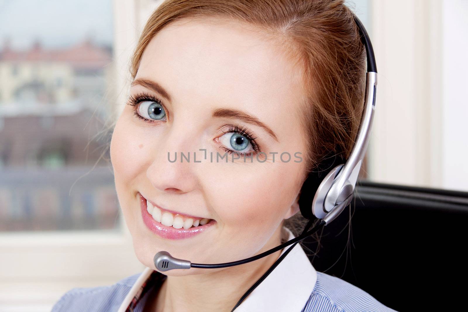 smiling young female callcenter agent with headset in office
