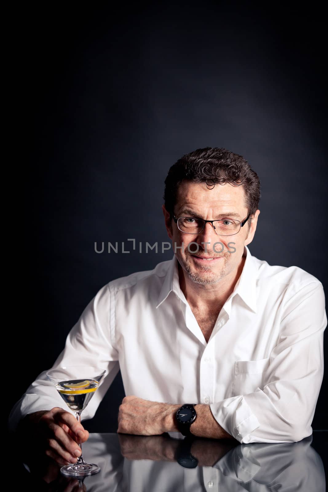adult man holding an alcoholic drink thoughtful on black background