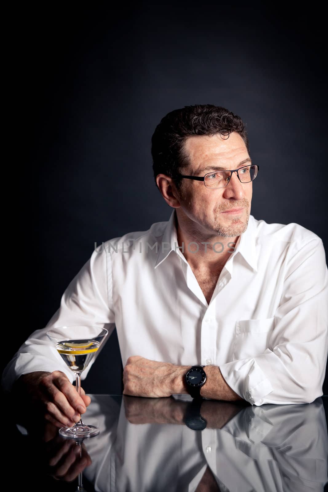 adult man holding an alcoholic drink thoughtful on black background
