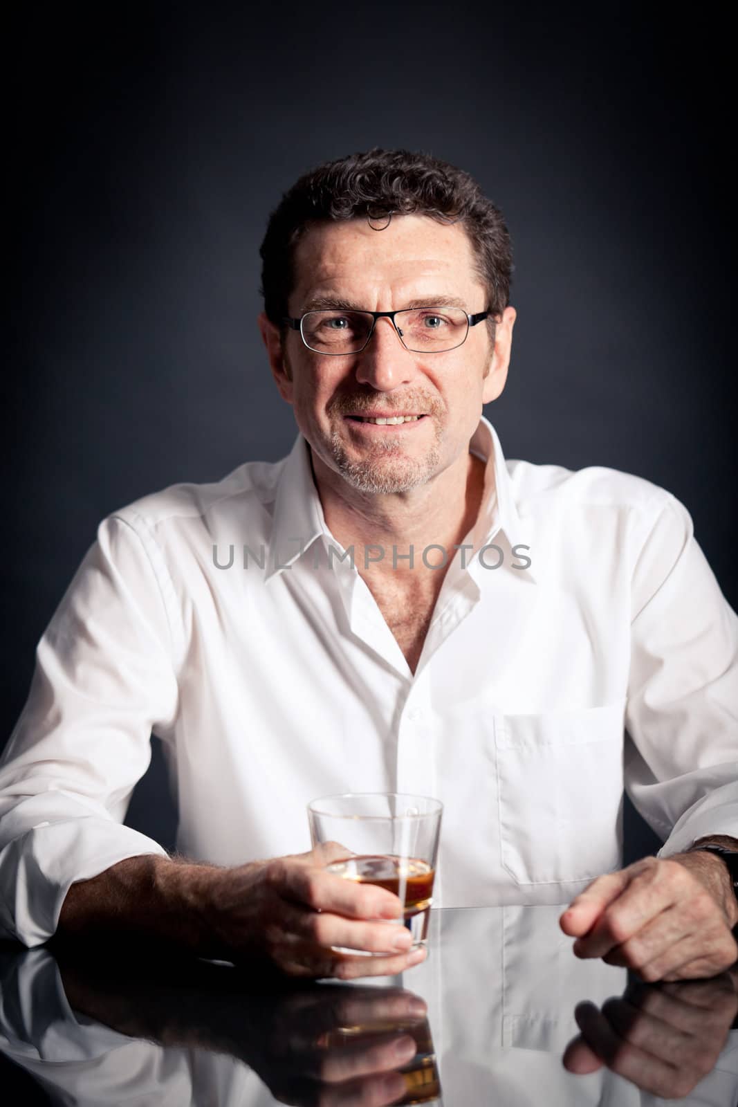 adult man holding an alcoholic drink thoughtful on black background