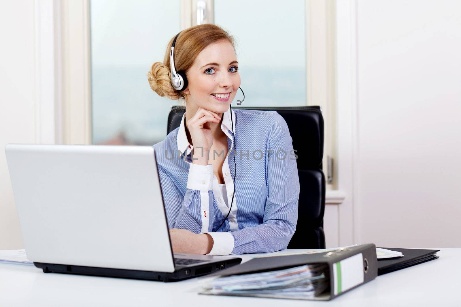 smiling young female callcenter agent with headset in office