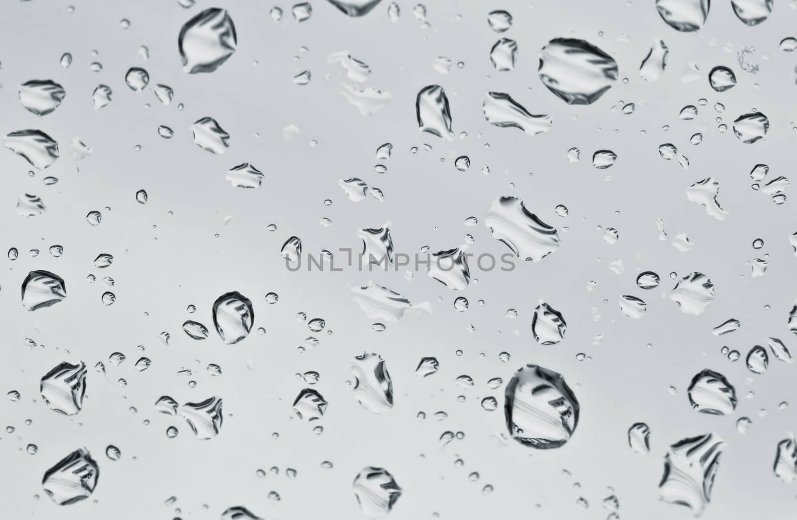 Close up of irregular water drops on glass by Jupe