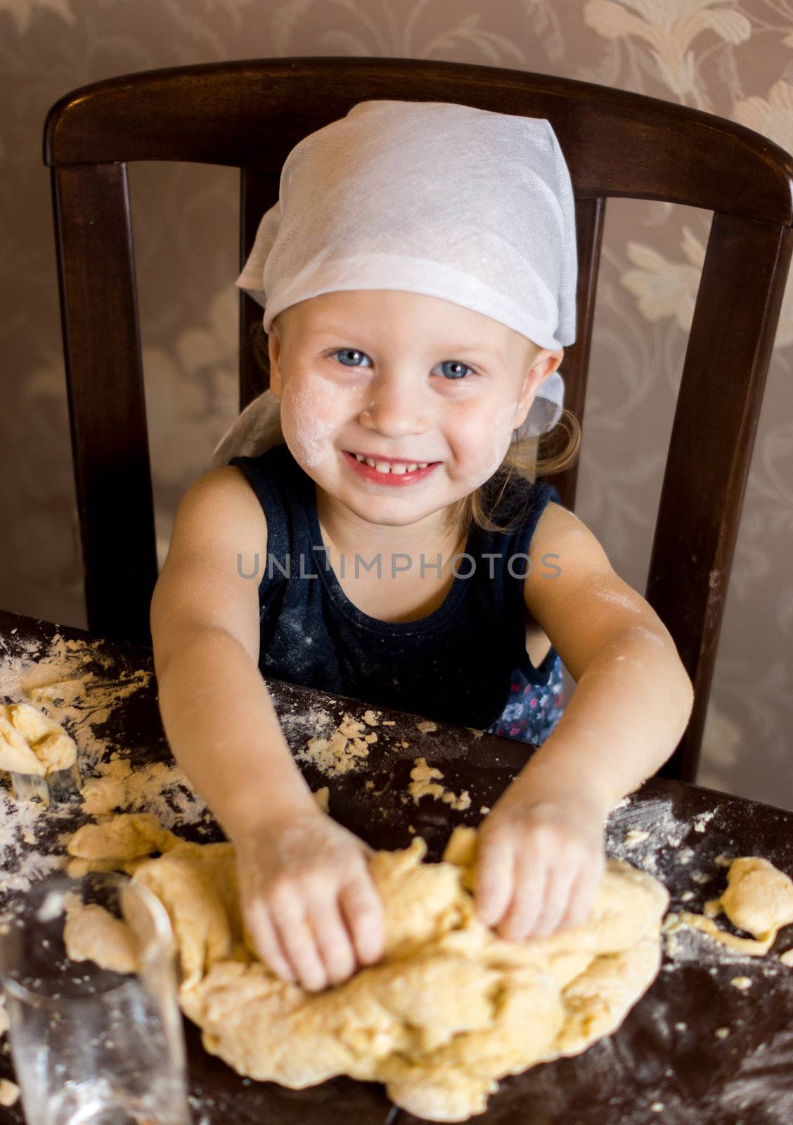 pretty little girl having fun kneads dough