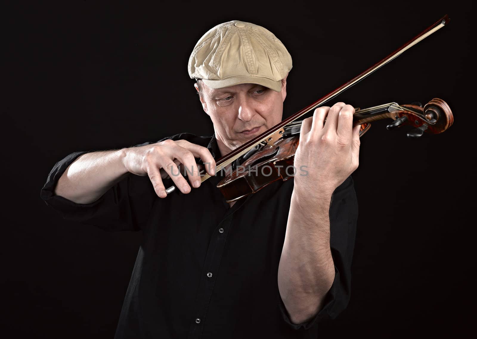 Portrait of a man playing  wooden violin on black background