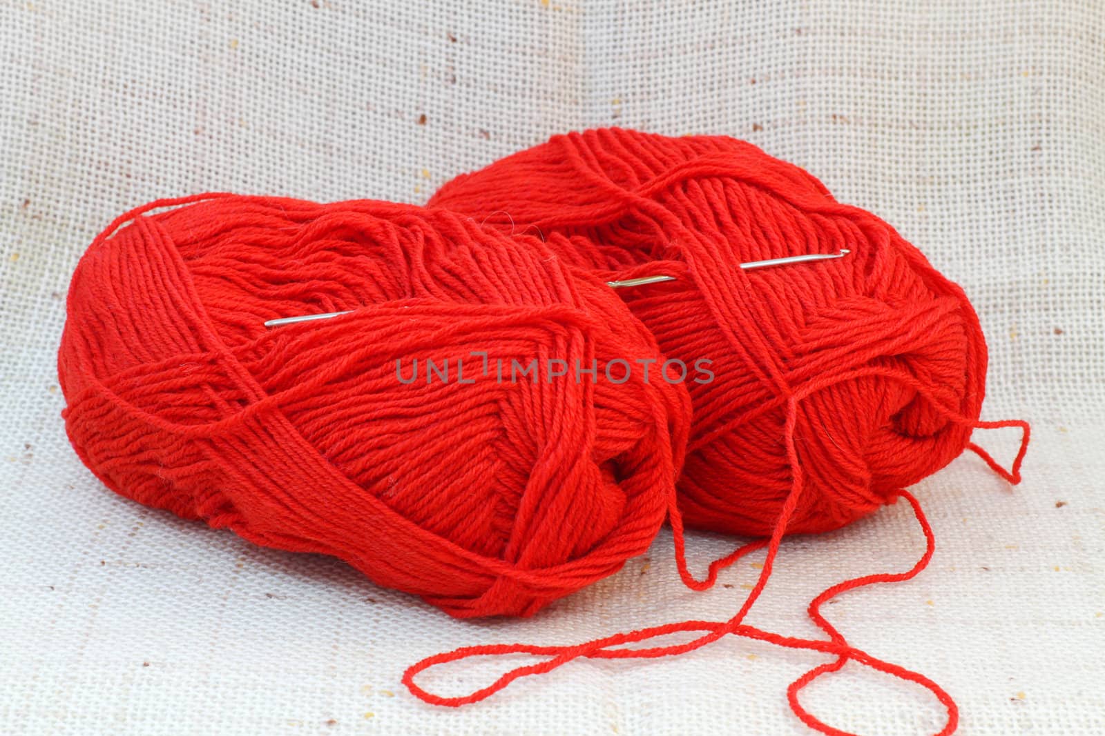 Close up of two red balls (clews) of yarn and knitting hook