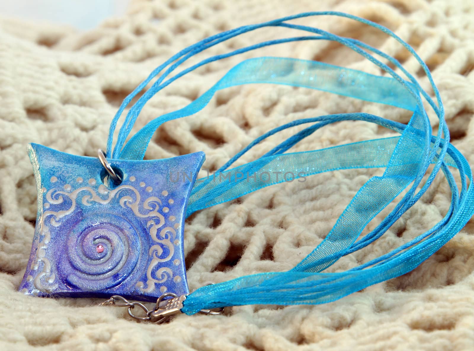 clay handmade blue amulet on a kntited background