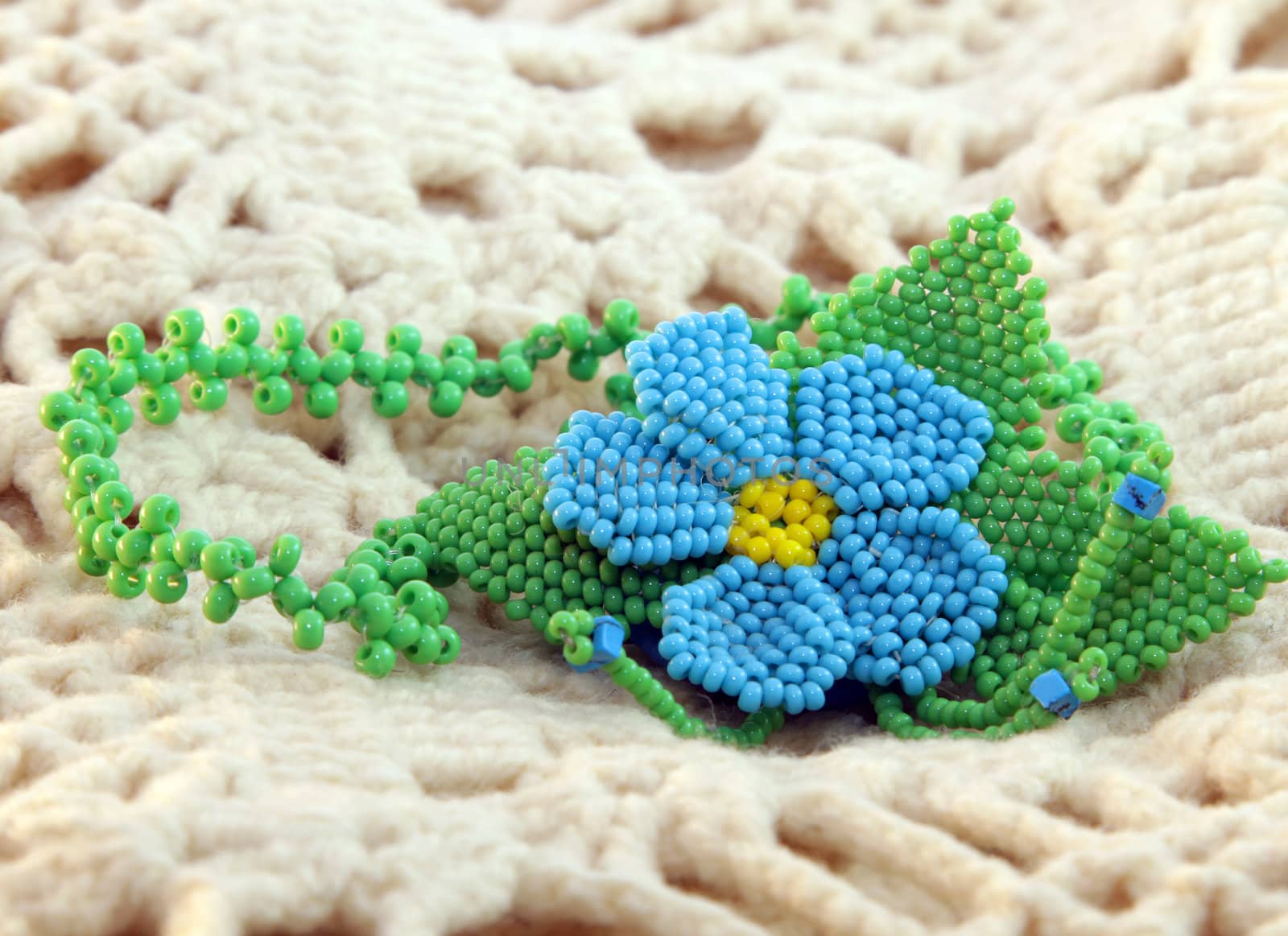 clay handmade blue bead pendant flower on a knitted background