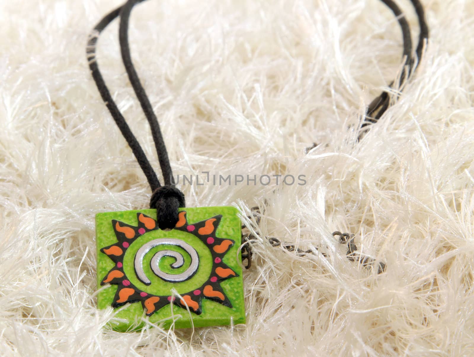 clay handmade green amulet (sun) on a knitted background