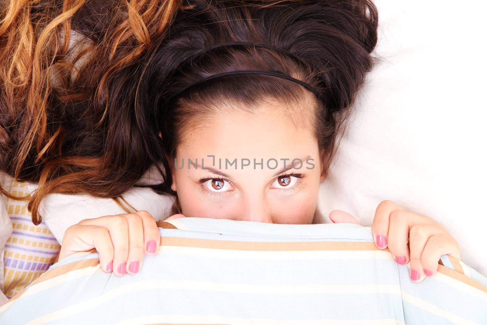 A young woman hiding under a blanket.