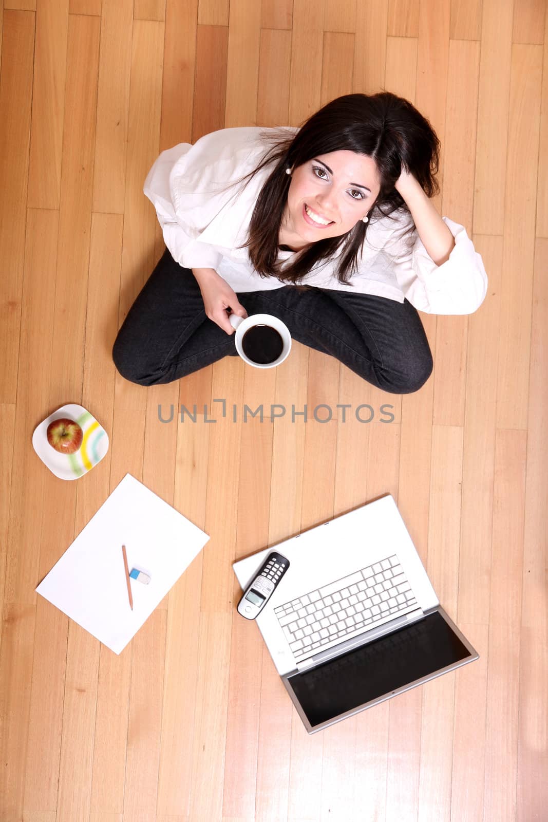 A young adult woman studying on the floor.