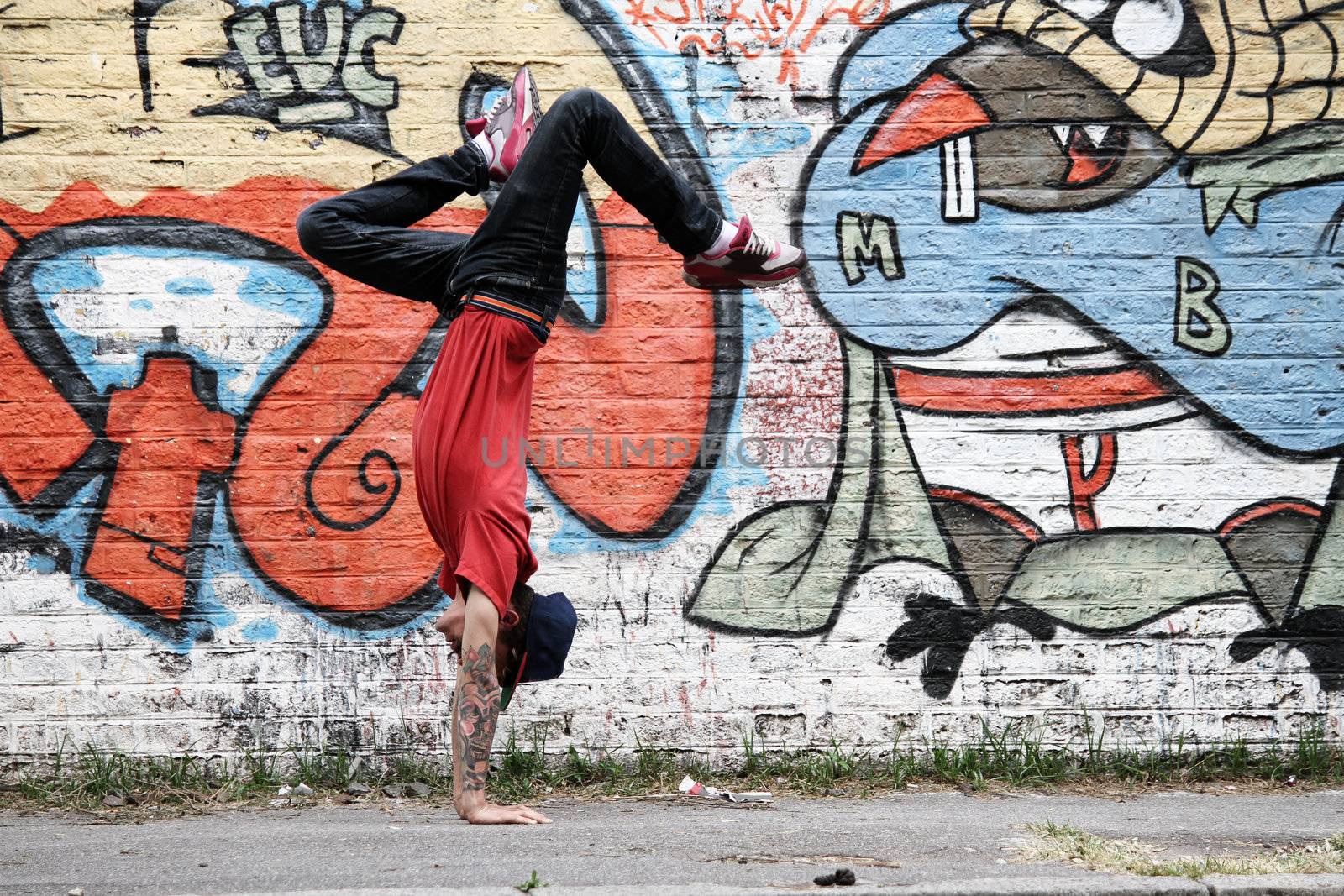 A performing HipHop Dancer in front of a Graffiti wall.