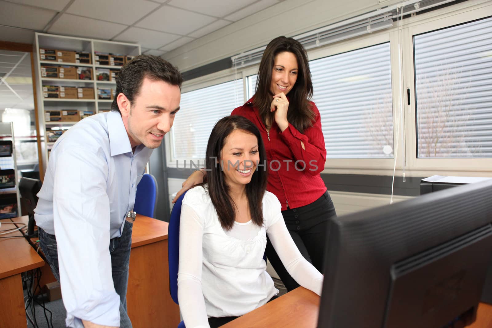 Smiling people using a computer in an office by phovoir