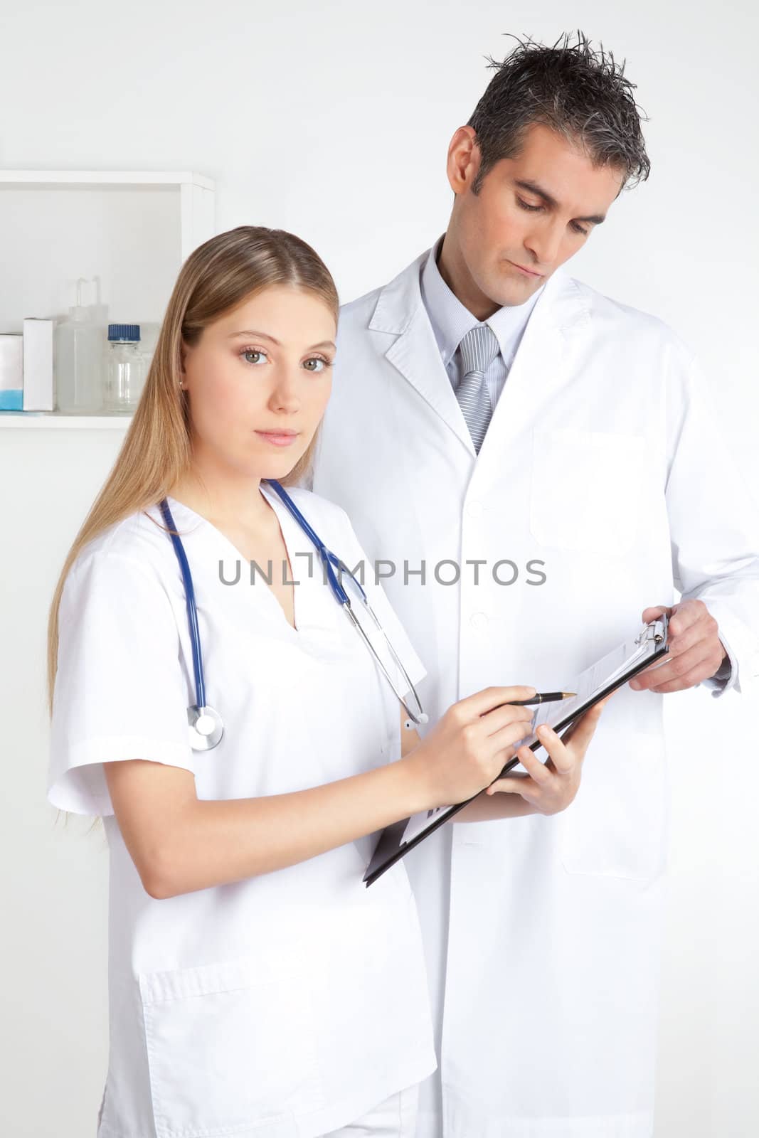 Female doctor showing clipboard to the male doctor.
