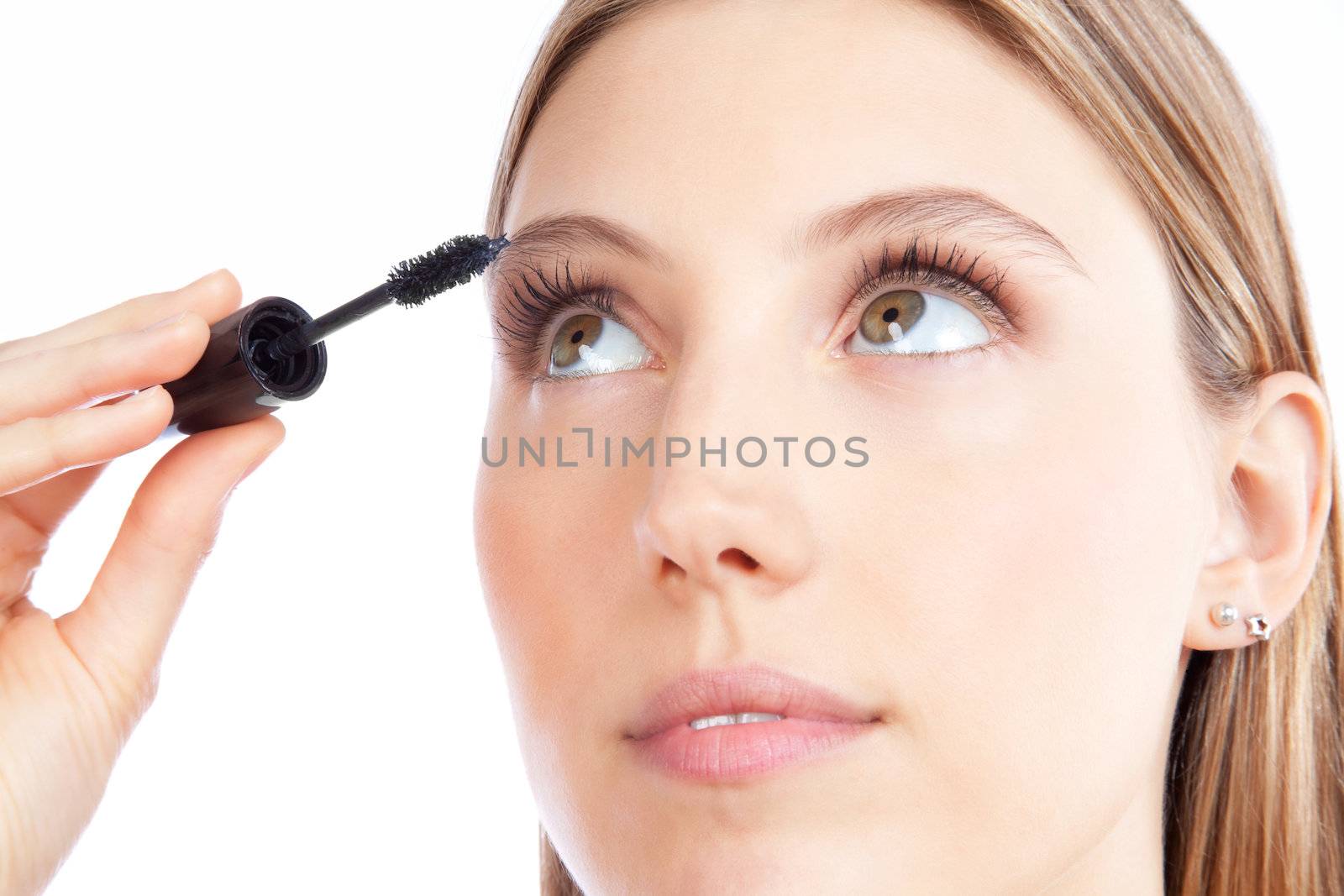 Beautiful woman applying mascara on her eyelashes.