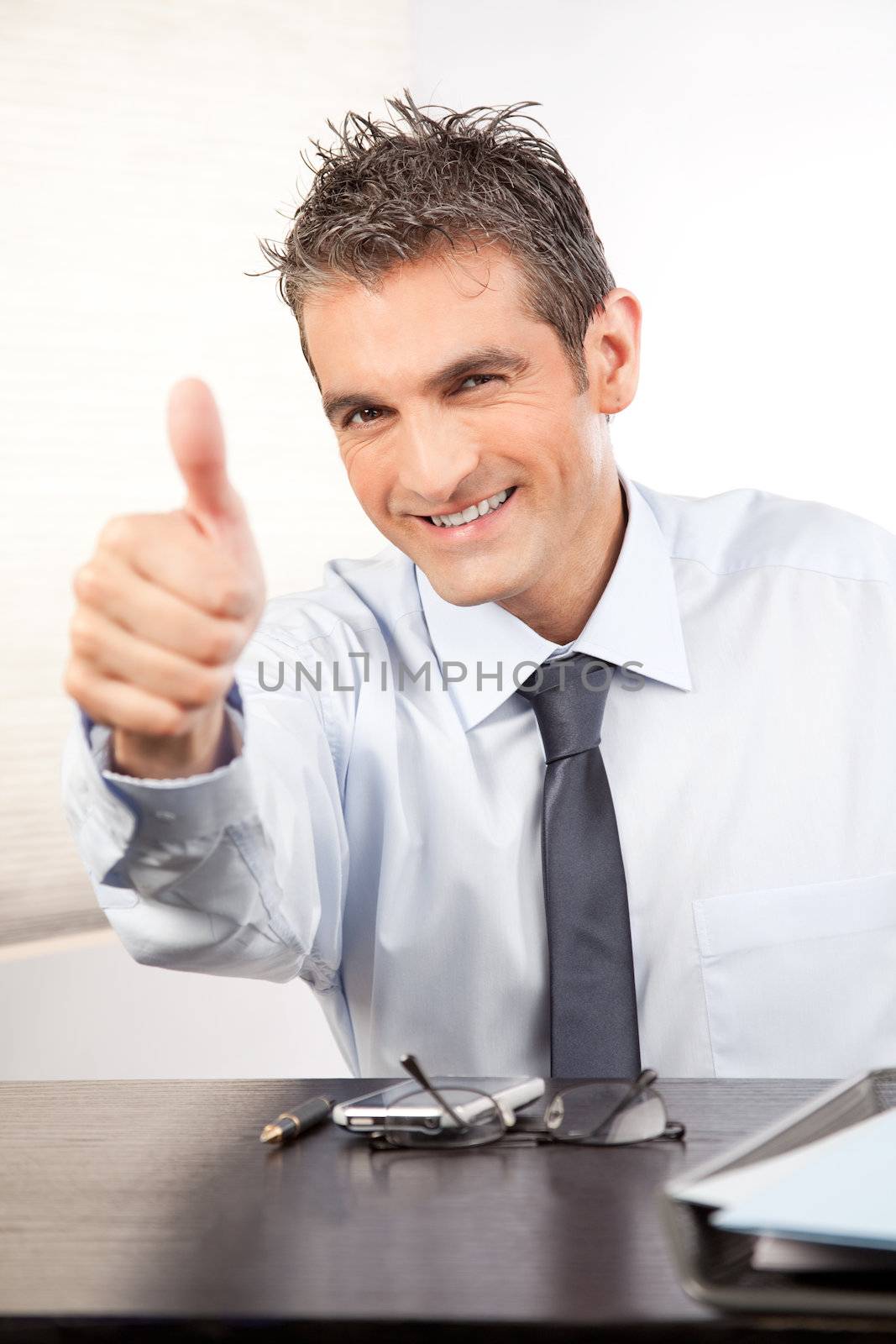 Businessman showing thumb up at work in office.