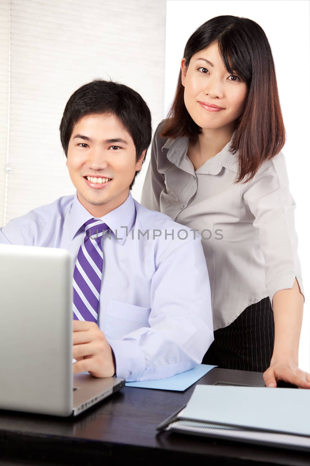 Businessman and businesswoman sitting at desk at work .