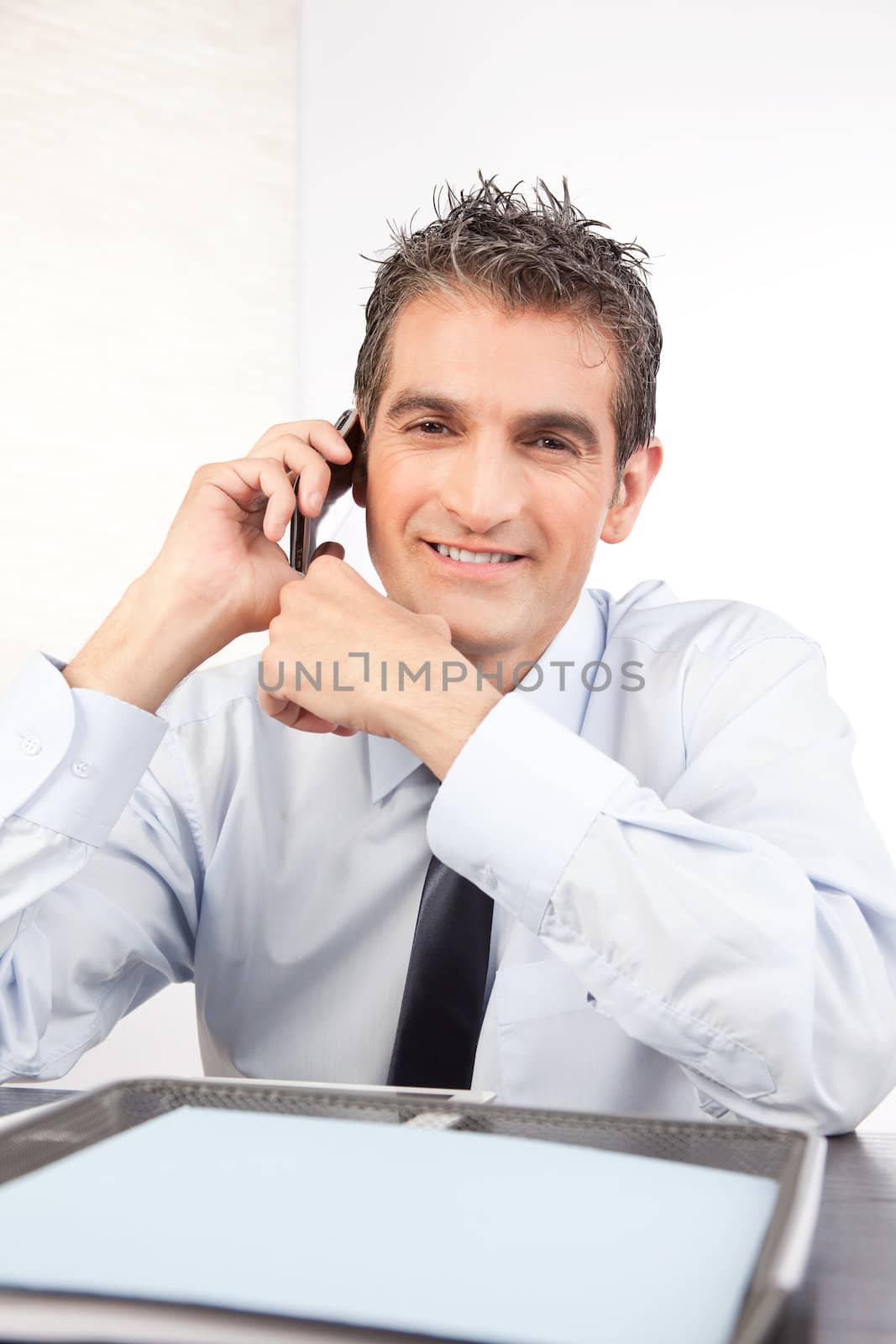 Businessman talking on cell phone at work isolated on white background.