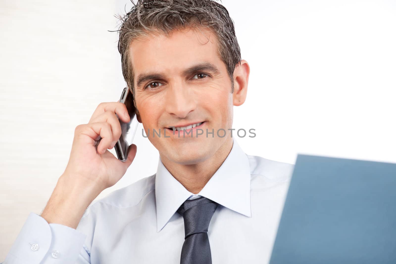 Businessman talking on cell phone at work isolated on white background.
