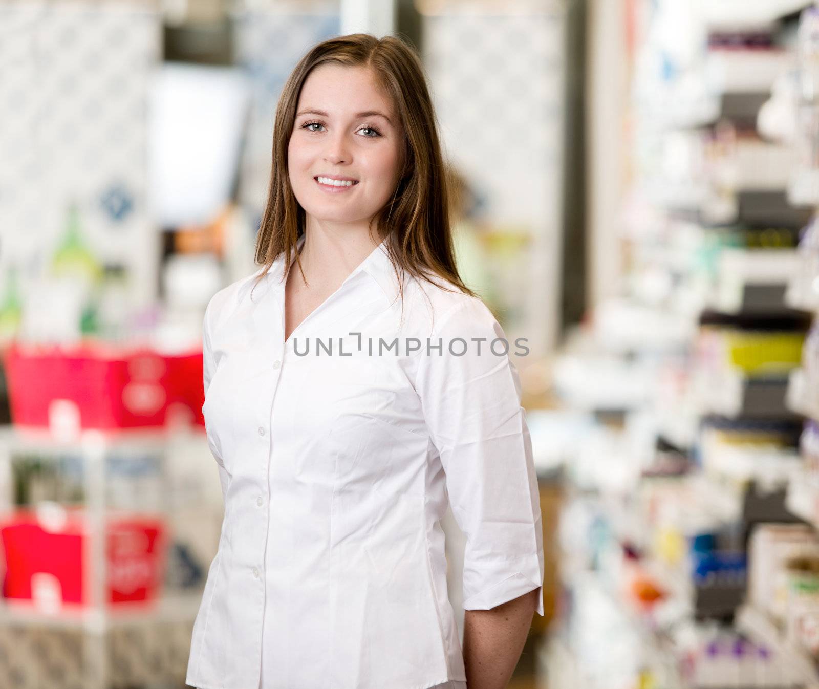 Portrait of a young attractive pharmacist standing in a pharmacy interior looking at the camera