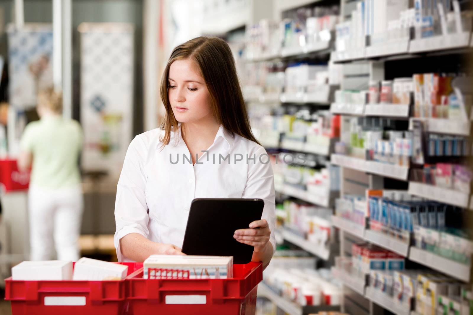 Female pharmacist working in pharmacy with digital tablet and medicine