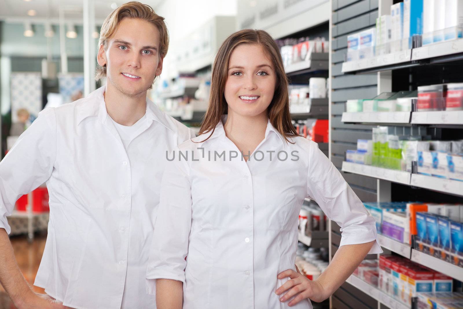 Portrait of male pharmacist technician standing with female colleague