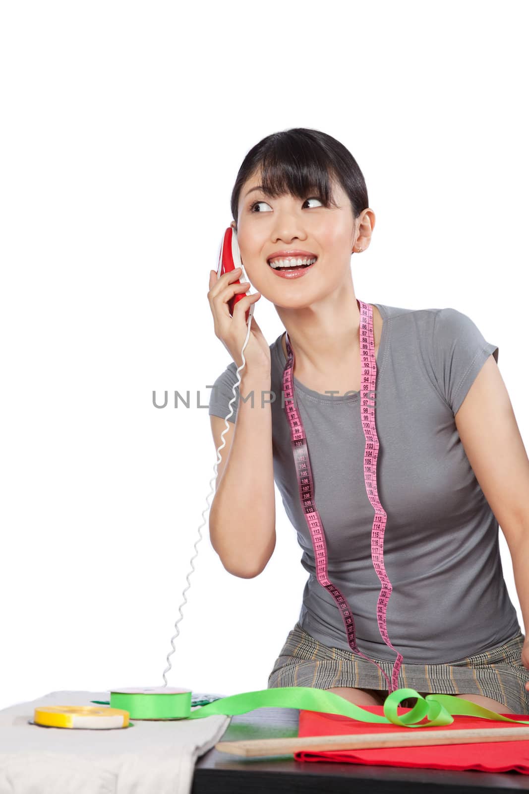 Young Asian woman dressmaker talking on phone.