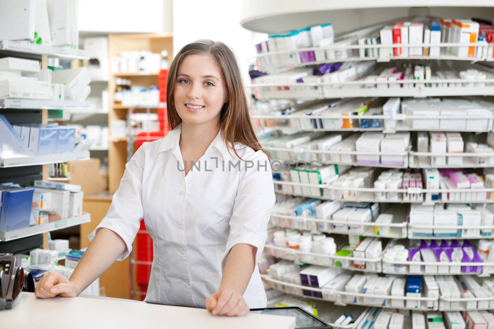 Portrait of female pharmacist standing at counter in pharmacy