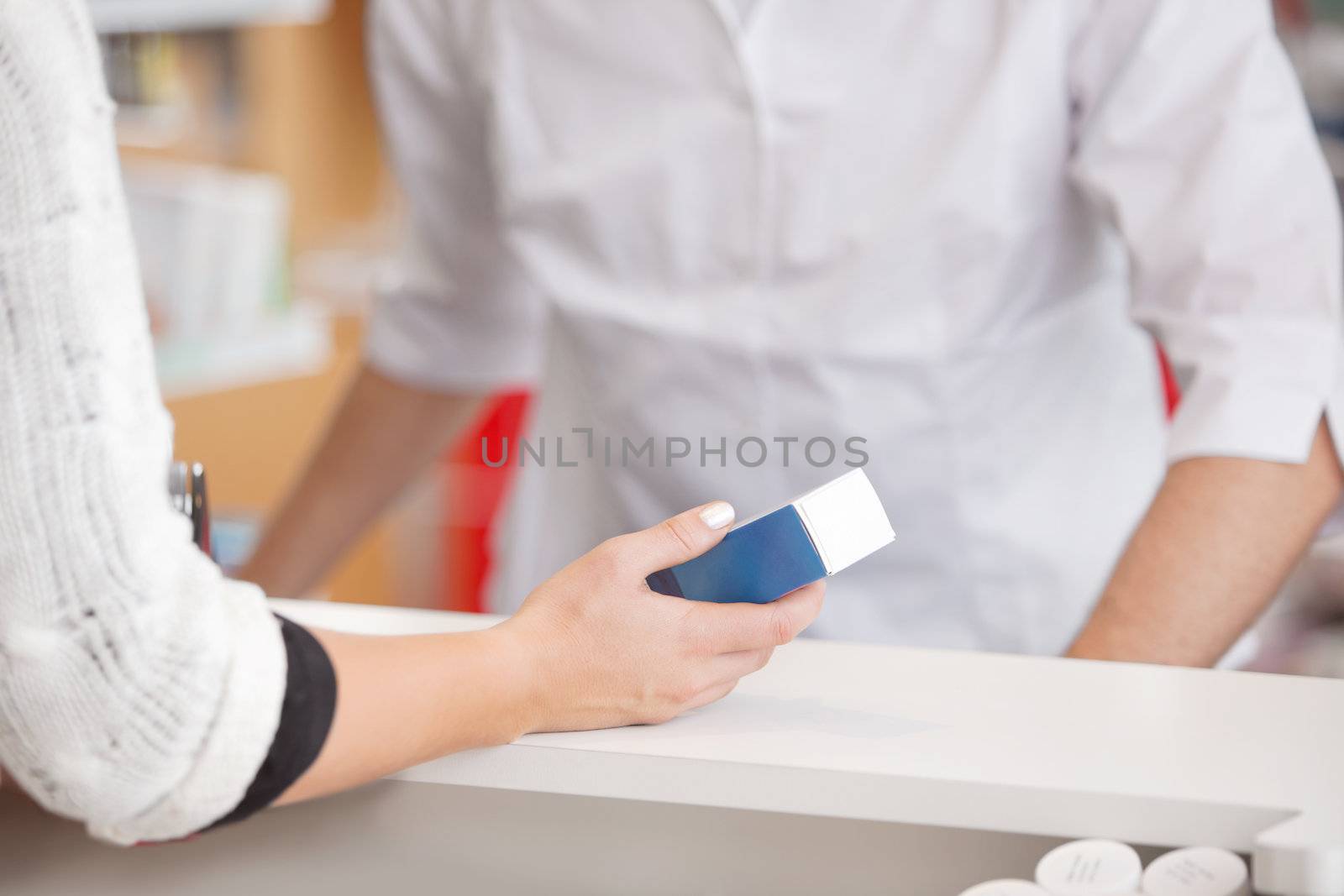 Female customer holding medicine box with pharmacist at counter