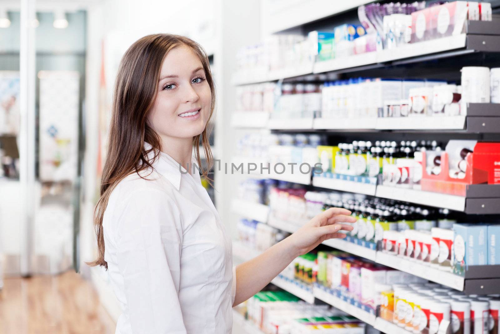 Portrait of young female pharmacist standing in pharmacy store