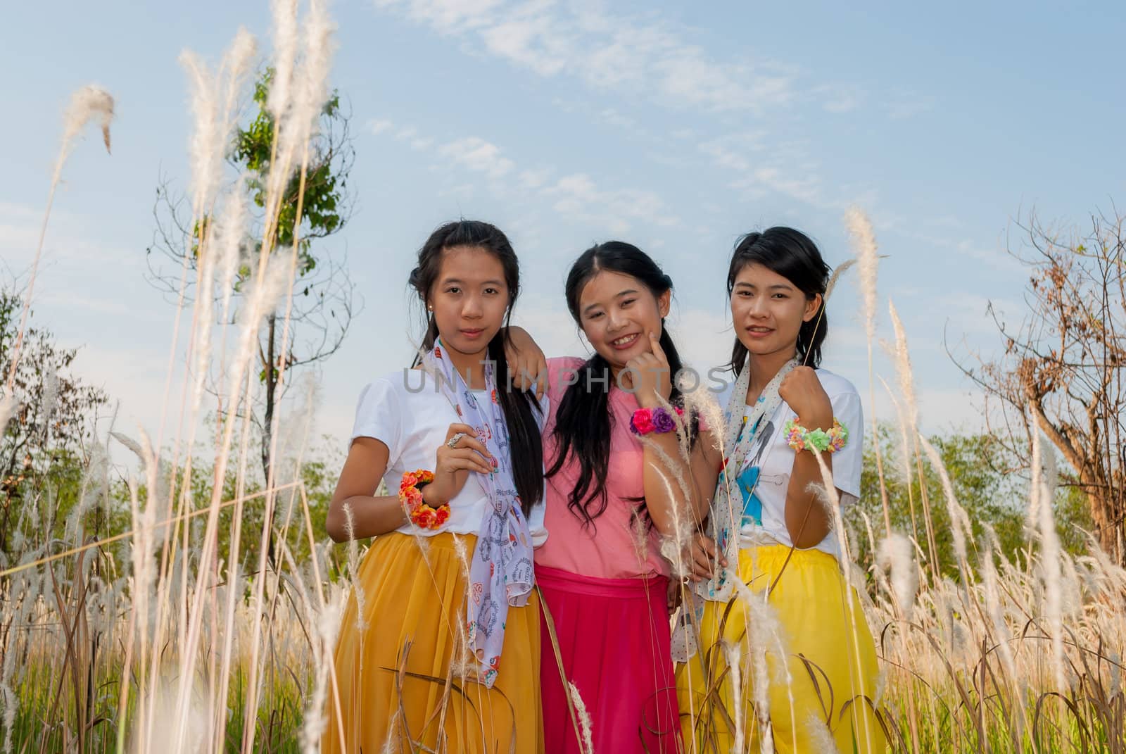 Asian Thai girls are standing together in the field.