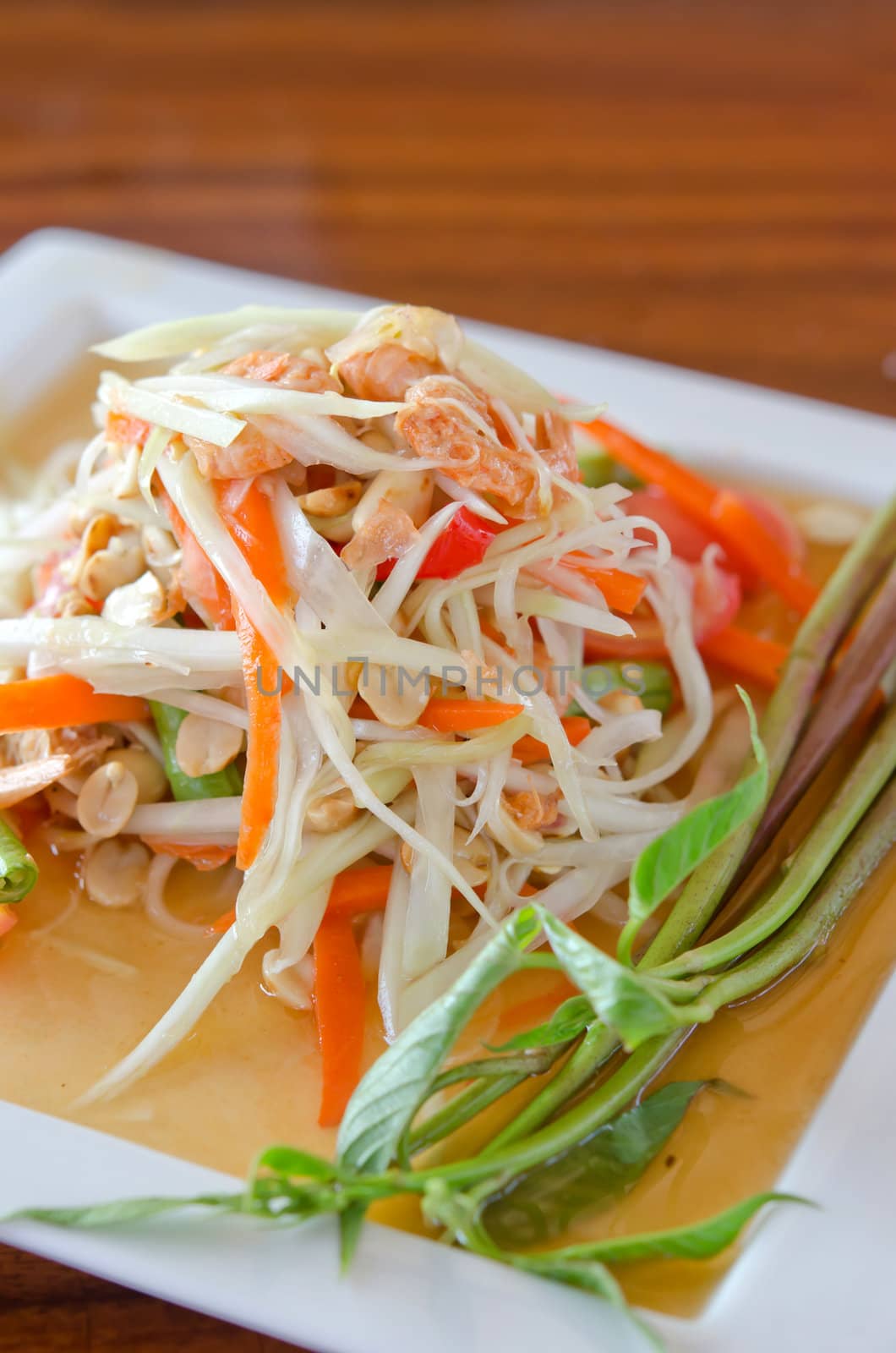 spicy papaya salad with peanut , dried shrimp and vegetable on white dish