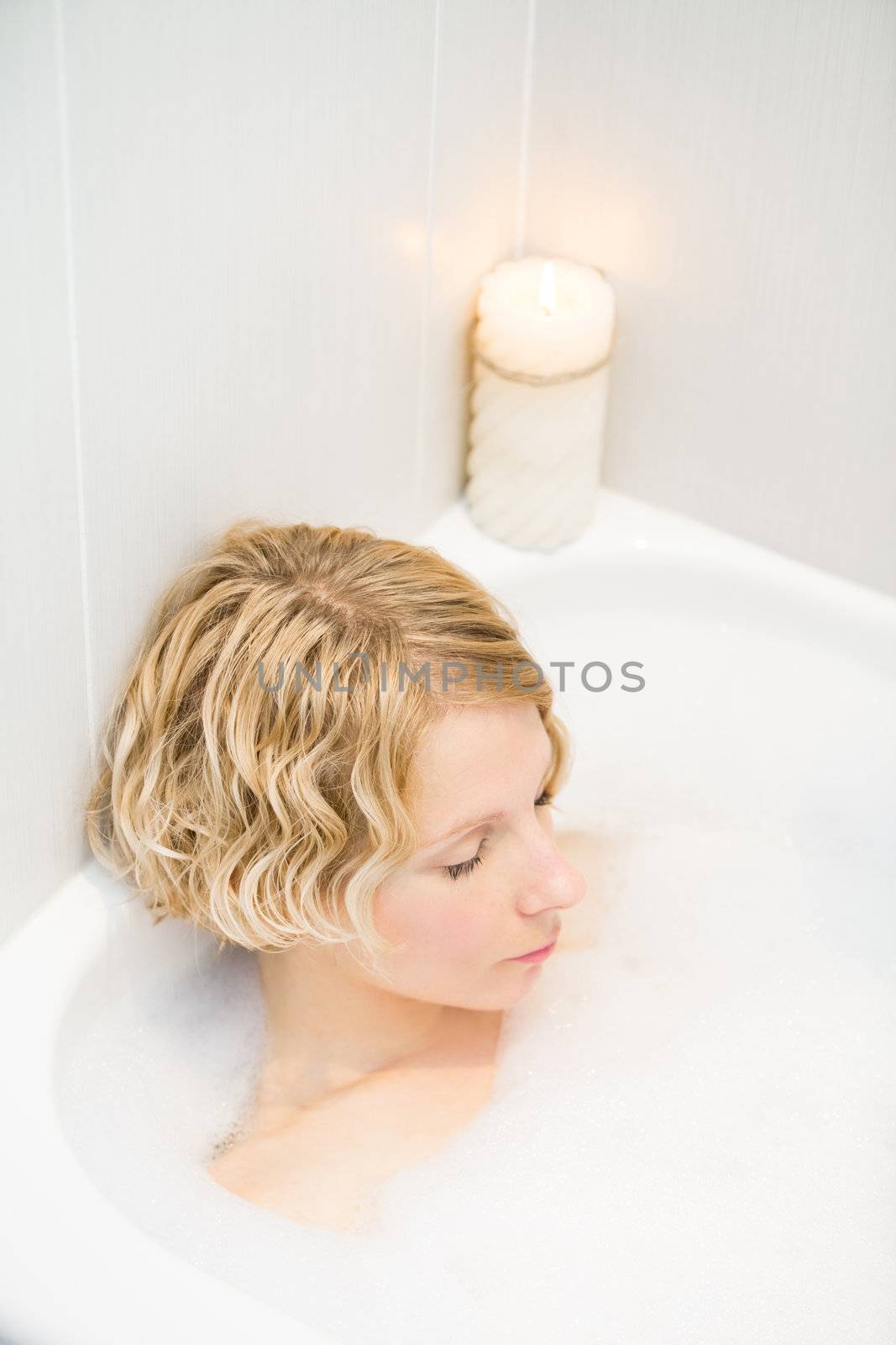 Young woman relaxing in the bath with candlelight
