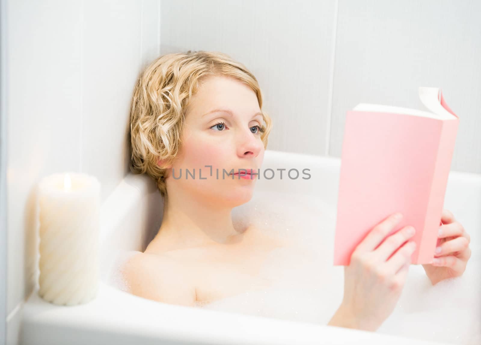 Young woman relaxing and reading a book in the bath  by aetb
