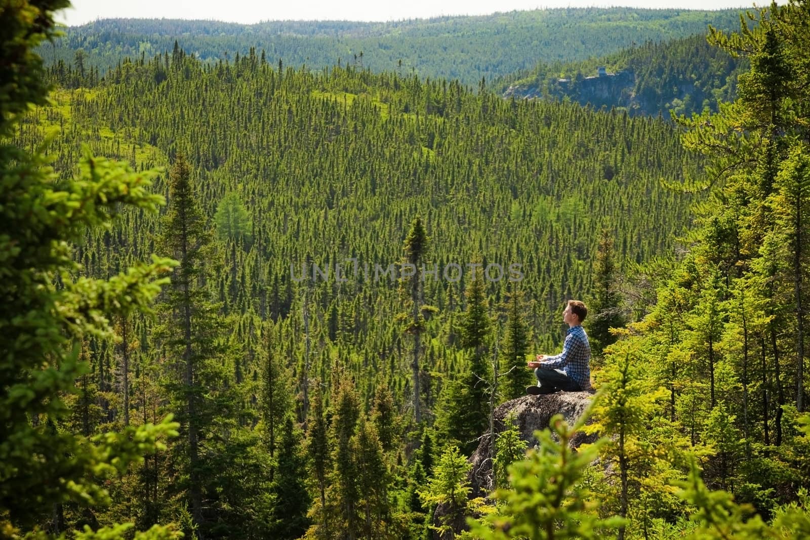 Young man on a rock in the middle of the nature