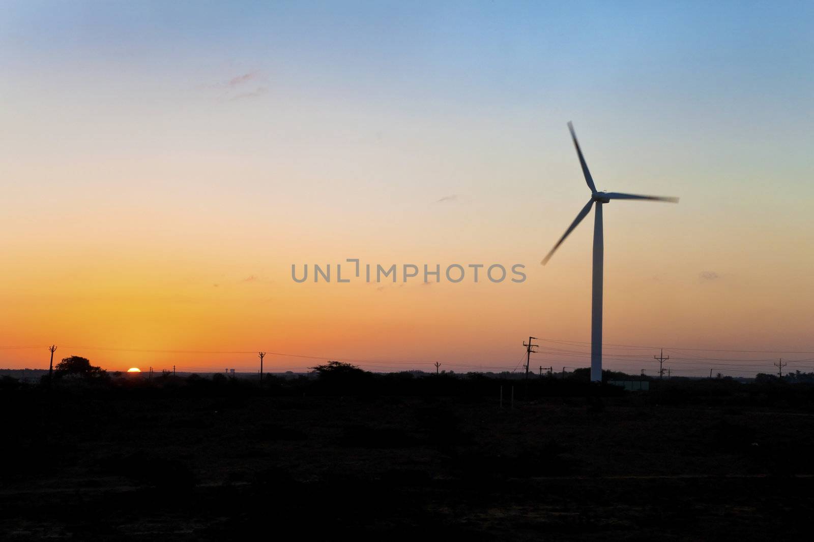 Horizontal image of barren land on the approach to Dwarka in Gujarat India. The sea breeze from the Arabian Sea is taken advantage of on plains with installation of wind powered generators for local infrastructure in the formm of electrical power