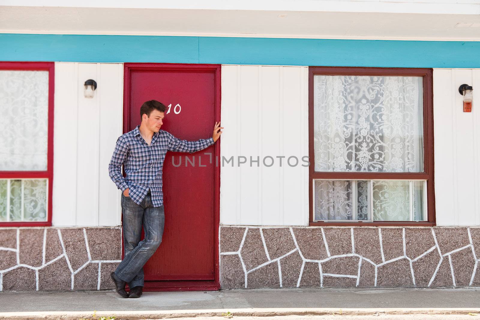 Young man in front of red door by aetb