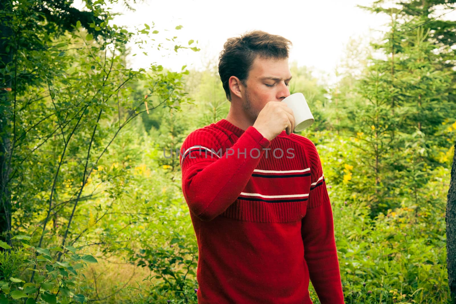 Young man in nature with a mug of coffee by aetb