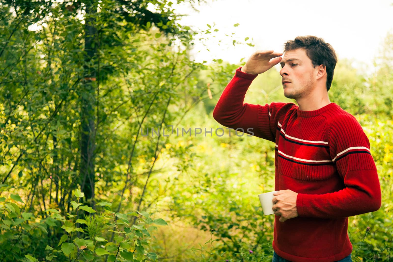 Young man in nature with a mug of coffee by aetb